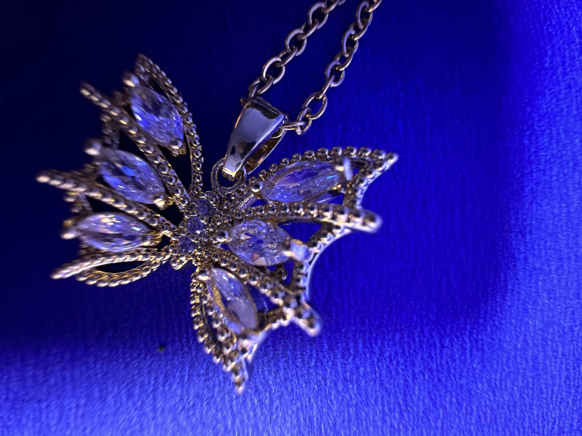 A silver-toned snowflake pendant necklace adorned with clear marquise-cut crystals, displayed on a vibrant blue textured background.